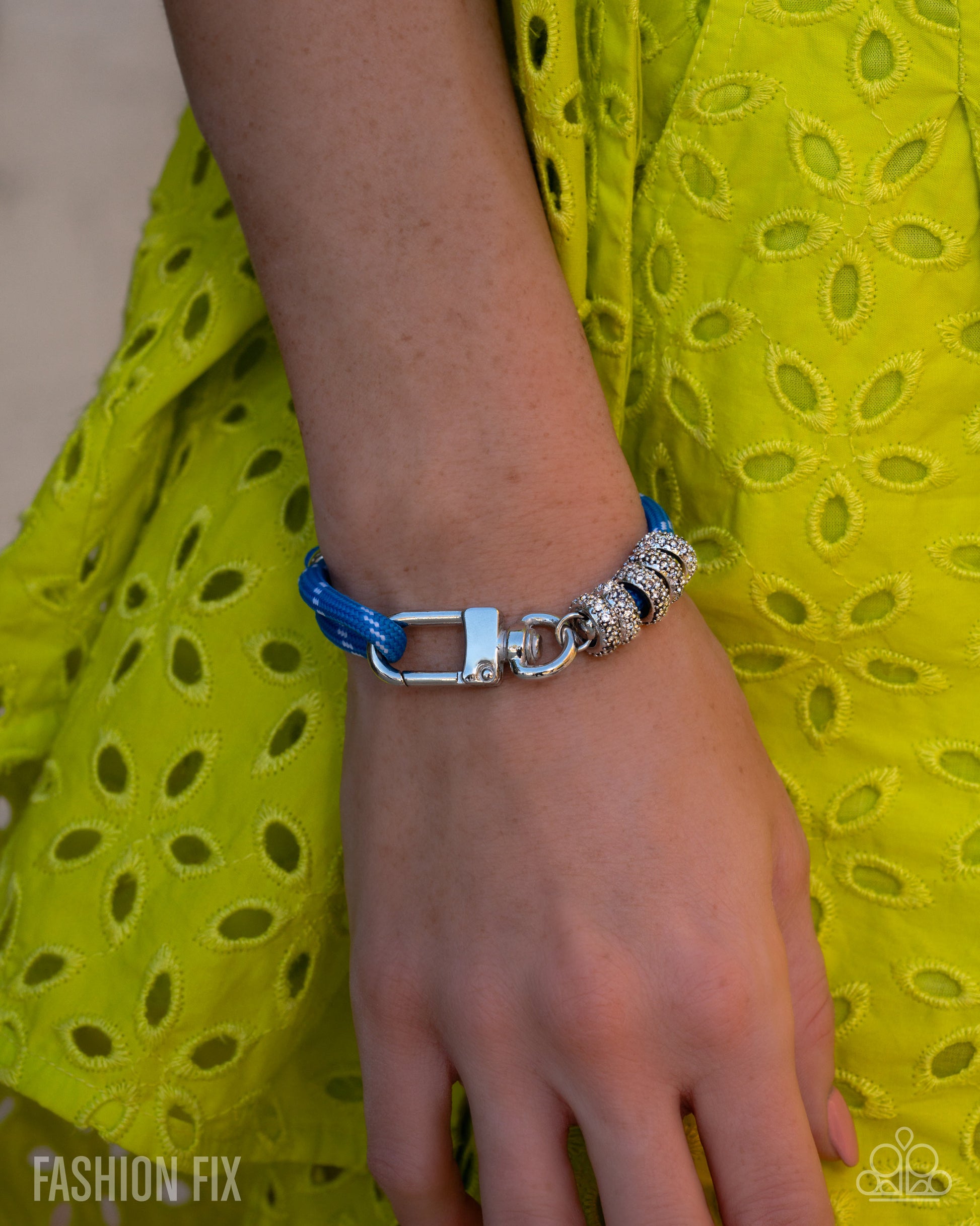 Bracelet with blue and silver design on wrist against a yellow fabric background