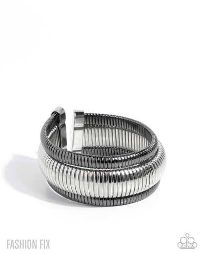 A silver-toned metal cuff bracelet with a textured, ribbed outer band and a smooth inner band, shown on a plain white background.