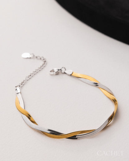 Two-toned gold and silver bracelet on a light gray surface with 'Cachet' branding.