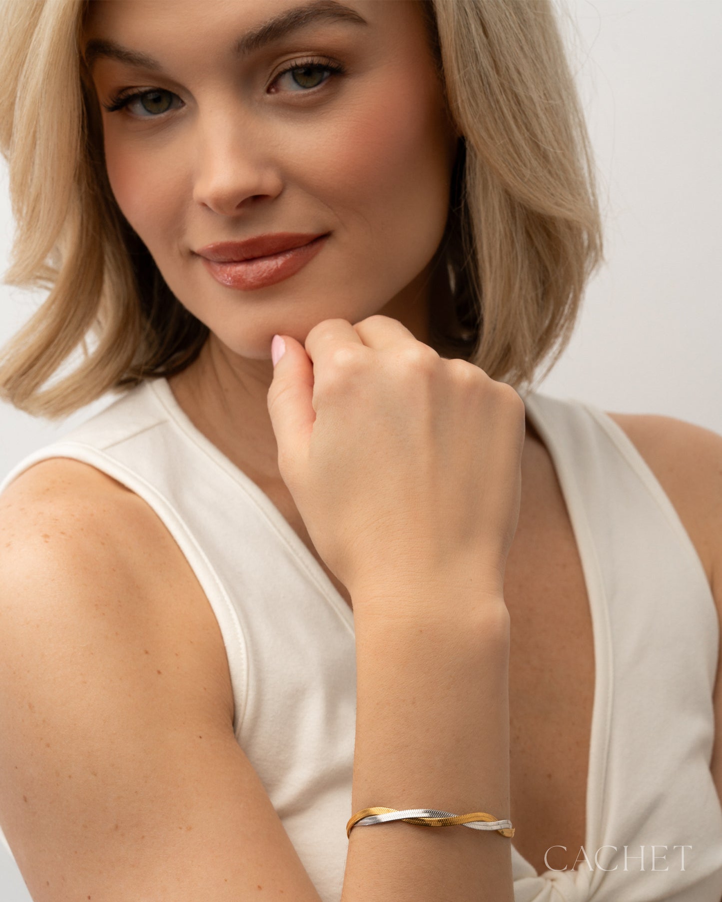 Woman wearing a gold bracelet on a plain background