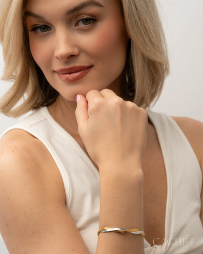 Woman wearing a gold bracelet on a plain background