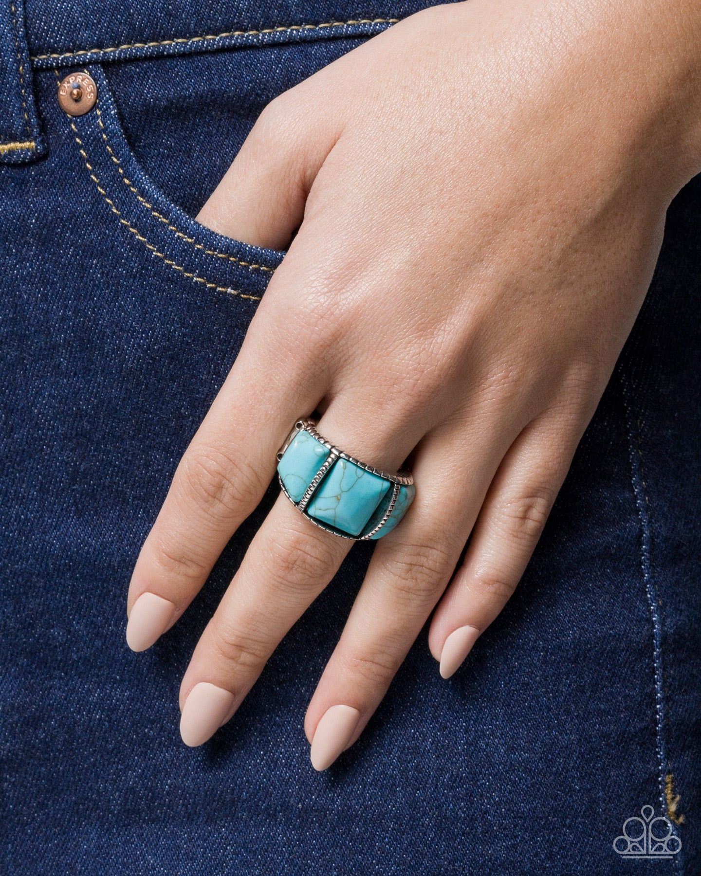 Turquoise ring on a hand against a denim background