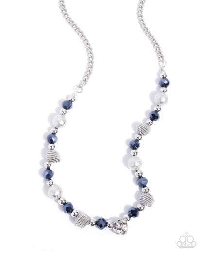 A silver beaded necklace featuring faceted navy blue beads, textured silver spiral discs, and clear crystal accents, displayed on a clean white background.