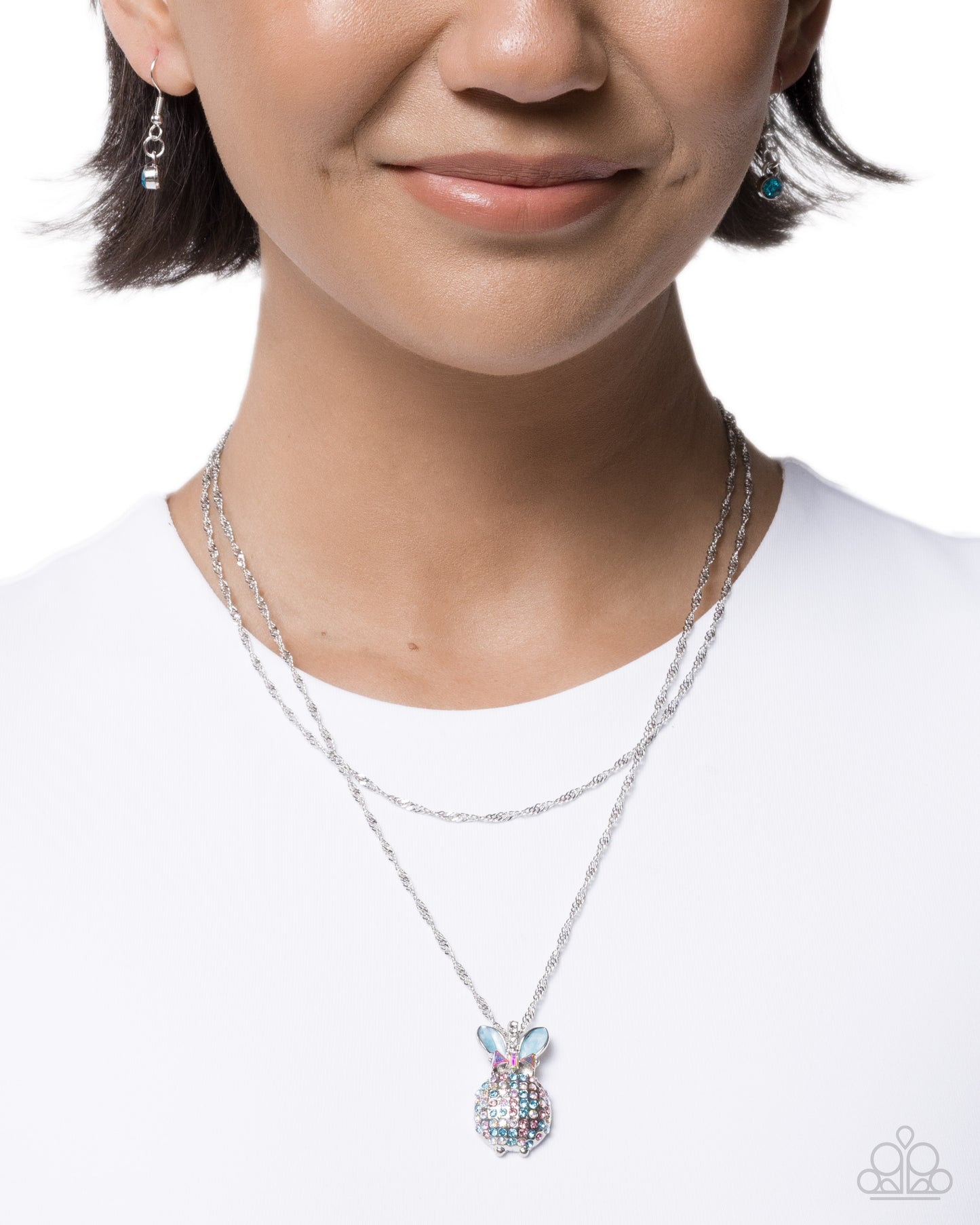 Person wearing a silver necklace with a butterfly pendant on a white background