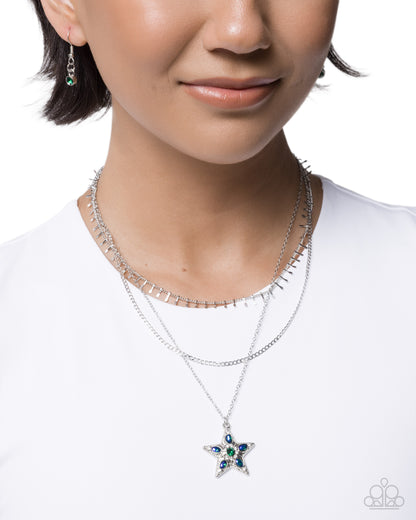 Close-up of a person wearing a star-shaped necklace with gemstones on a white background