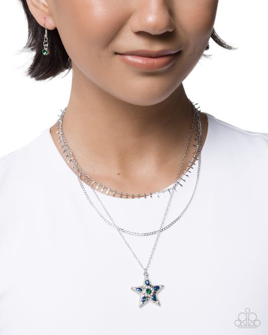 Close-up of a person wearing a star-shaped necklace with gemstones on a white background