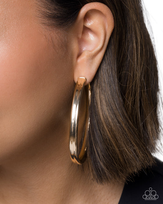 Gold hoop earring worn by a person with brown hair.