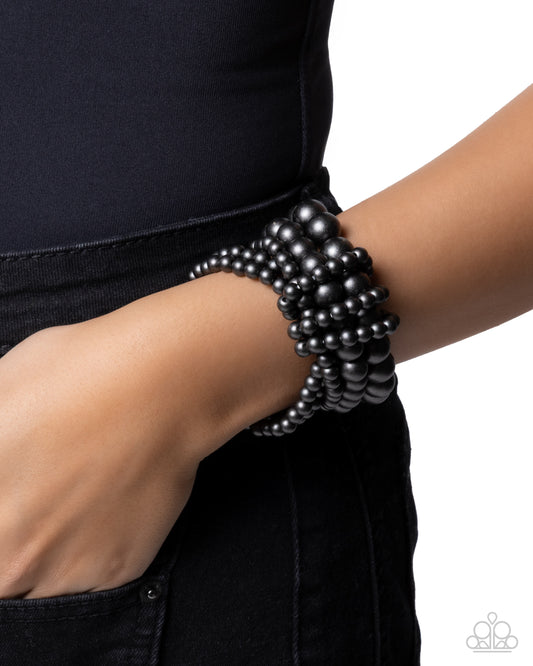 Black beaded bracelet on a wrist against a white background