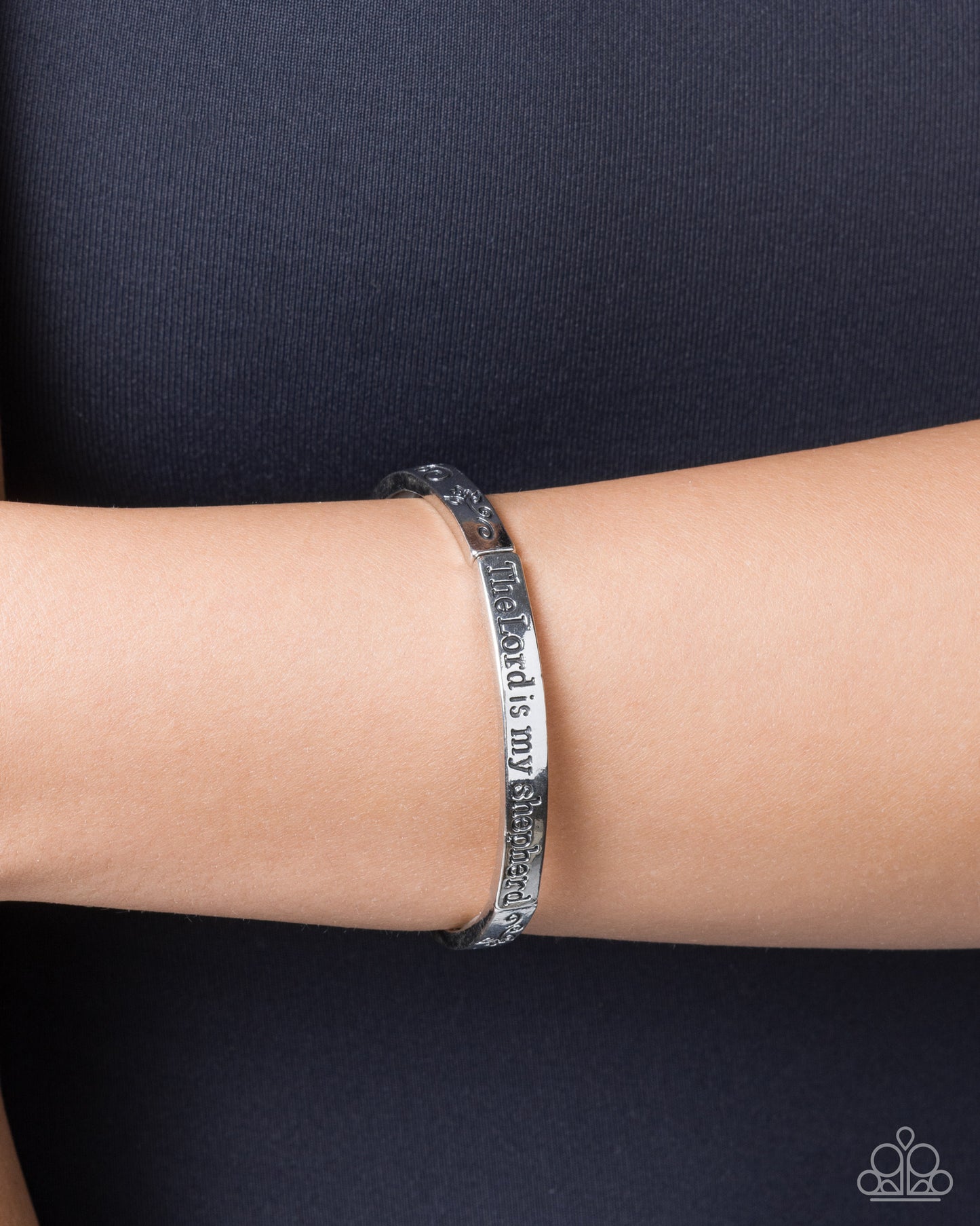 Silver bracelet on a wrist against a dark background