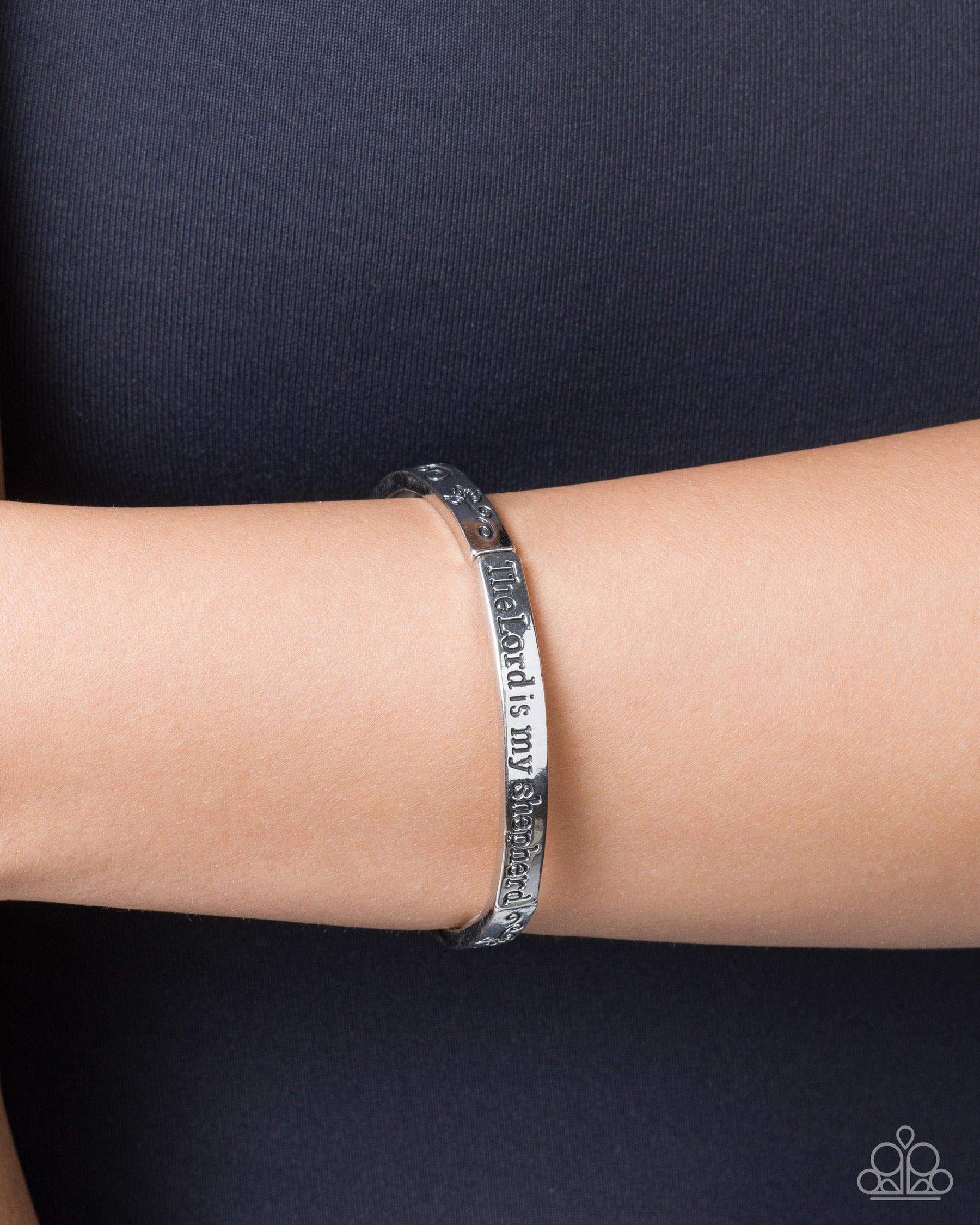 Silver bracelet on a wrist against a dark background