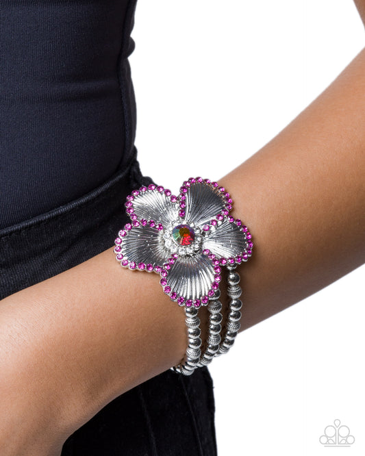 Silver flower bracelet with pink accents on a wrist against a white background