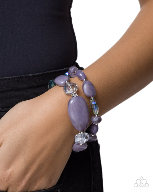 Purple beaded bracelet on a wrist with a white background