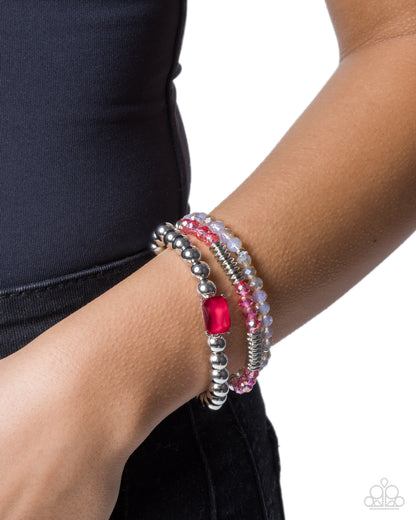 Bracelet with pink and red gemstones on a wrist against a white background