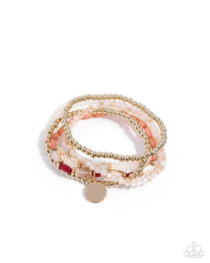 A stack of three beaded wrap bracelets on a white background. The bracelets feature gold-tone beads, light pink beads, faux pearl white beads, and a small red accent bead with a round rose gold charm.