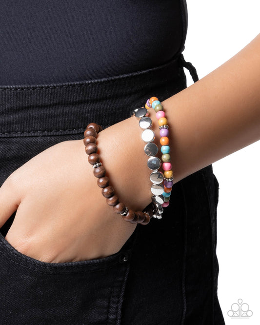 Two bracelets on a wrist against a black background