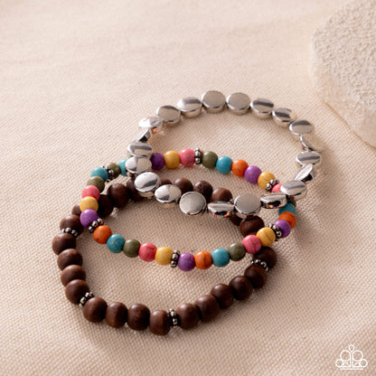 Two bracelets, one with colorful beads and the other with silver beads, on a beige surface.