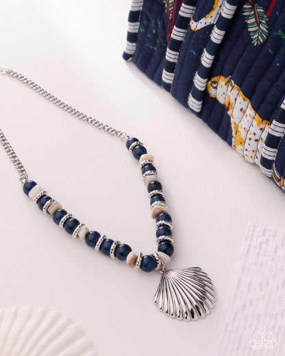 Necklace with blue beads and a shell pendant on a white surface