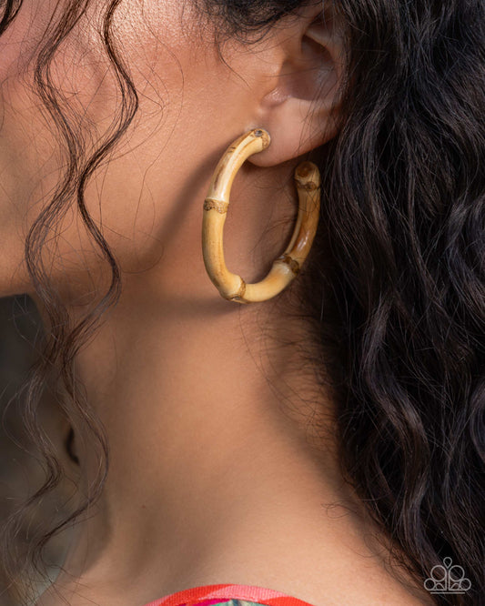 Close-up of a person wearing a gold hoop earring with hair and shoulder visible.