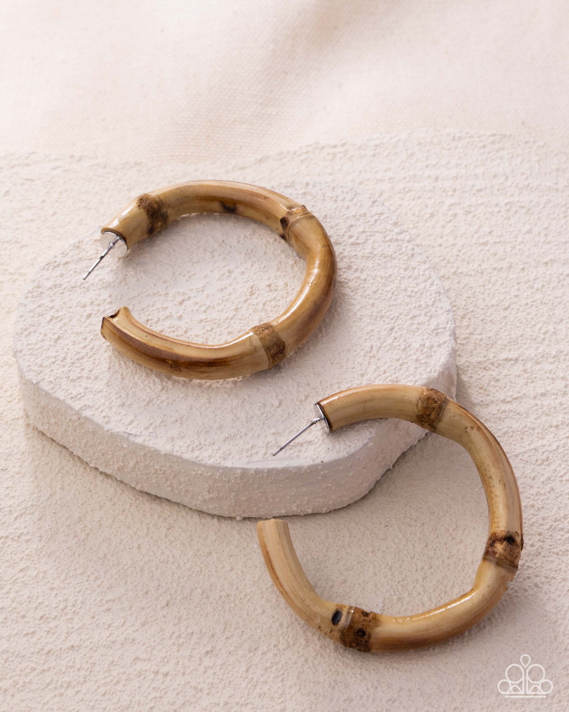 Pair of brown hoop earrings on a textured white surface