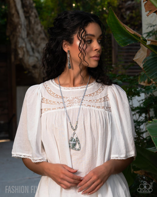 Woman wearing a white dress with lace details in an outdoor setting