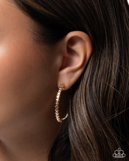 Gold hoop earring worn by a person with dark hair.