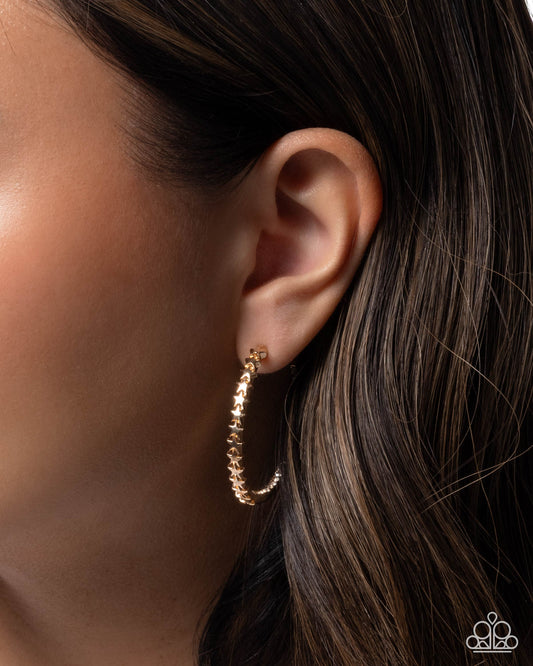 Gold hoop earring worn by a person with dark hair.