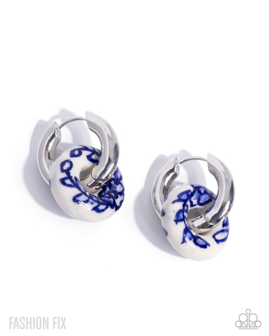 Pair of hoop earrings with blue floral design on white background