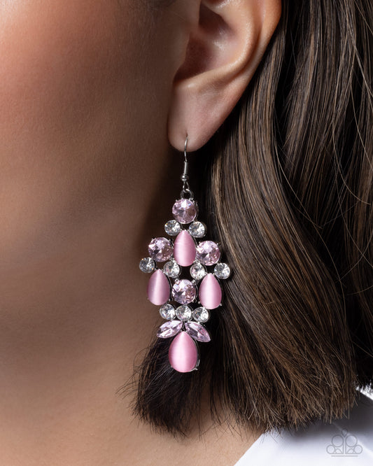 Close-up of an earring with pink and clear gemstones on a blurred background