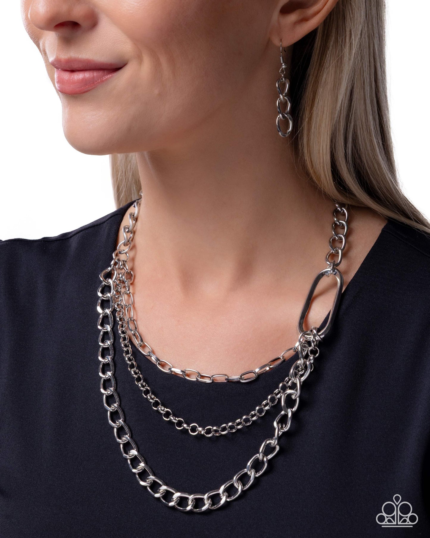 Woman wearing a silver chain necklace and earrings on a white background