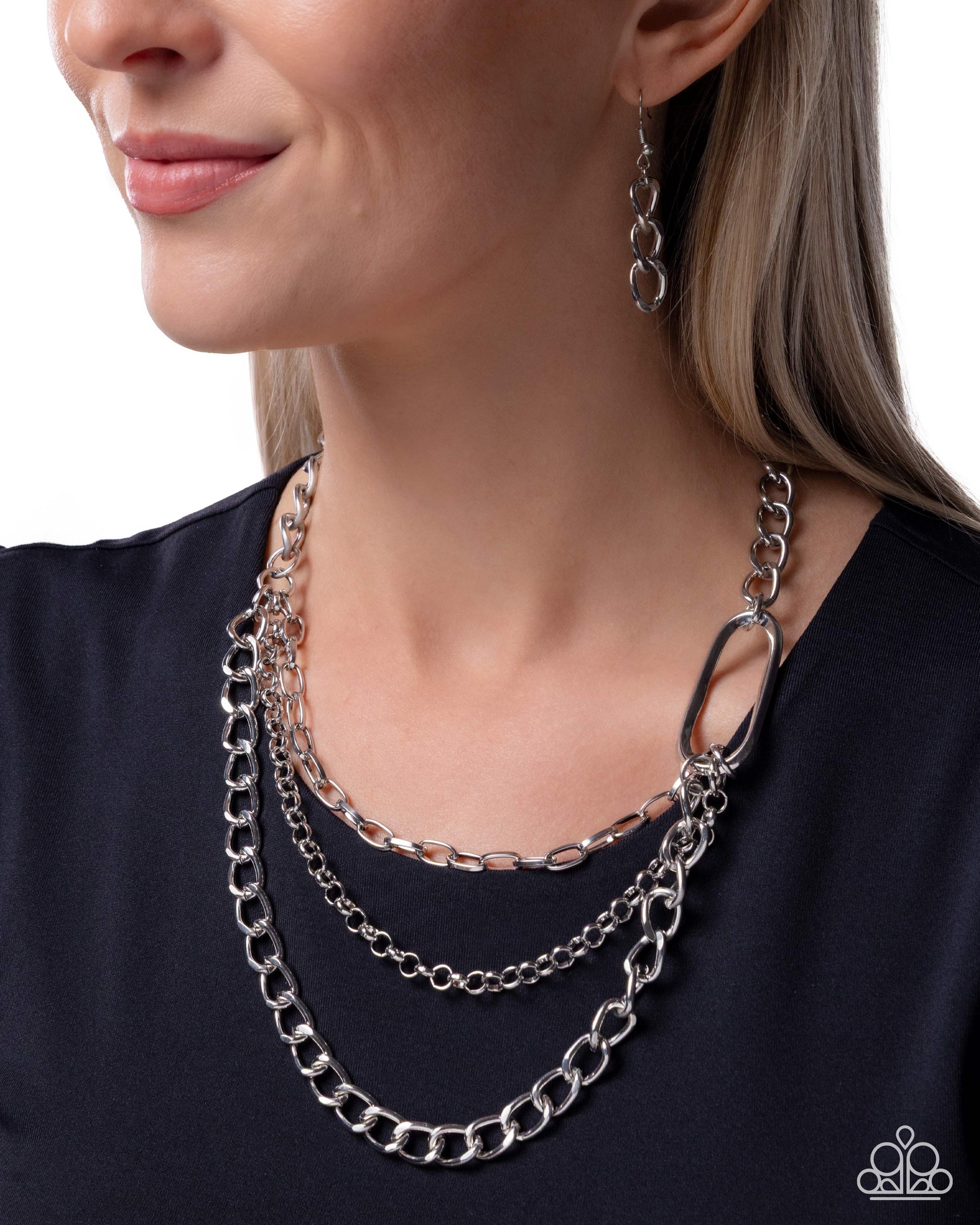 Woman wearing a silver chain necklace and earrings on a white background