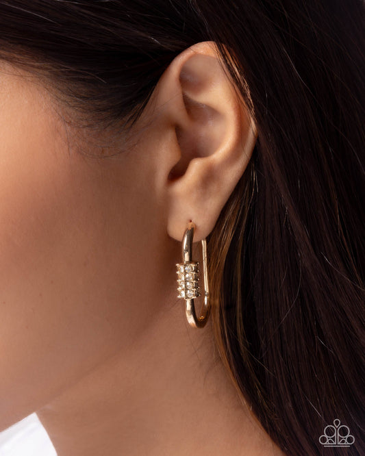 Gold hoop earrings worn by a person with dark hair.