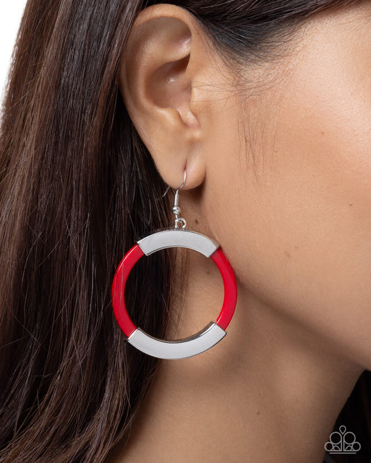 Close-up of a person wearing a red and silver hoop earring.