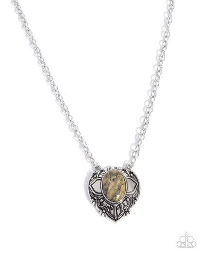 Silver necklace with a heart-shaped pendant featuring a stone on a white background