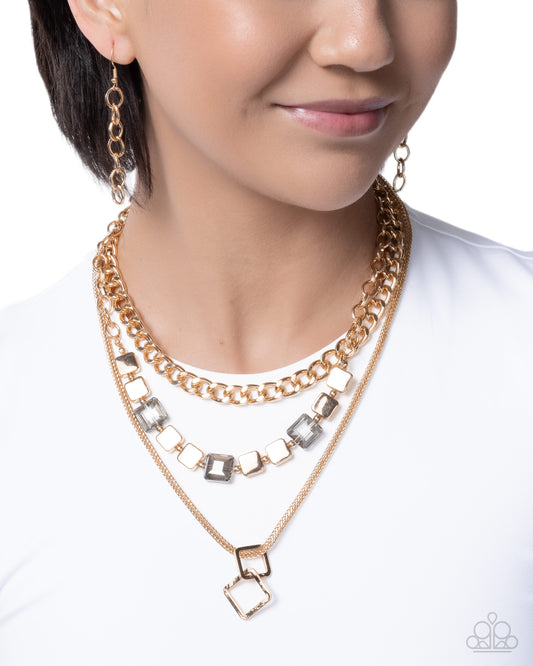 A close-up of a woman wearing a layered gold necklace set with square-cut clear rhinestones and matching drop earrings, against a white background.