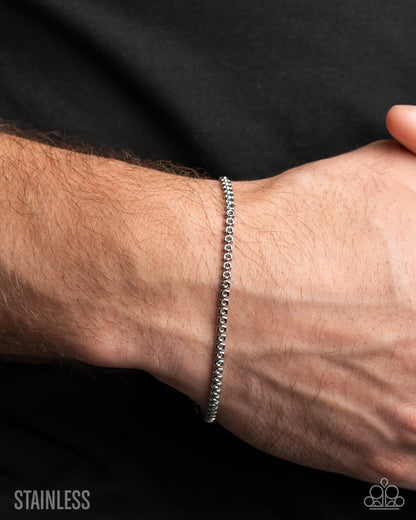 Silver bracelet on a wrist with a black background