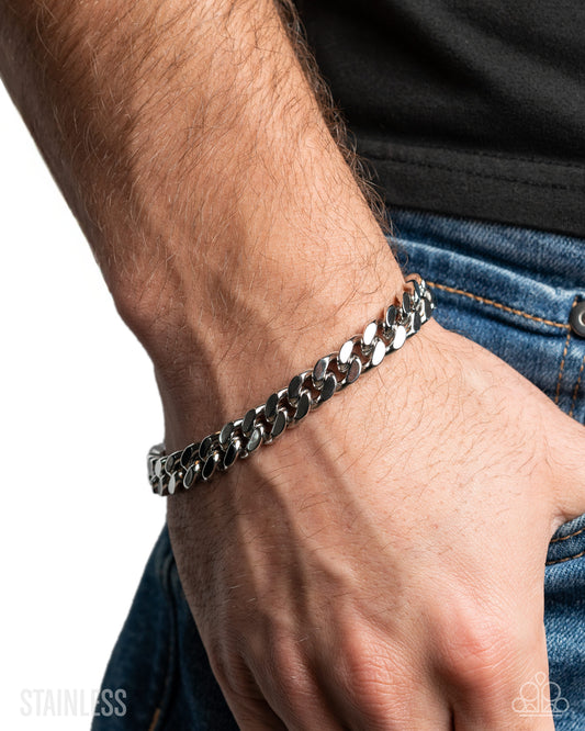 Close-up of a person's wrist wearing a silver chain bracelet on a white background