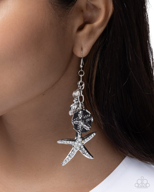Starfish-shaped earring worn by a person with dark hair.