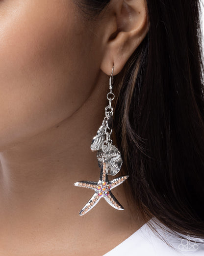 Starfish-shaped earrings with rhinestones worn by a person