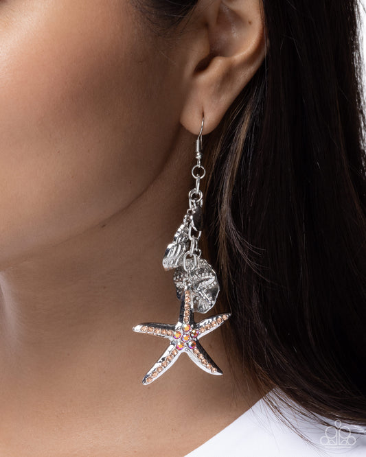 Starfish-shaped earrings with rhinestones worn by a person