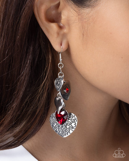 Close-up of an ear wearing a silver earring with red gemstones.