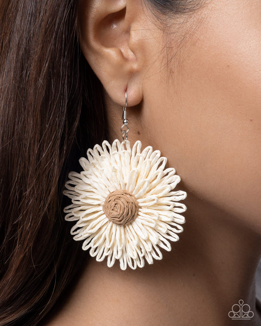 Close-up of a beige floral earring worn by a person