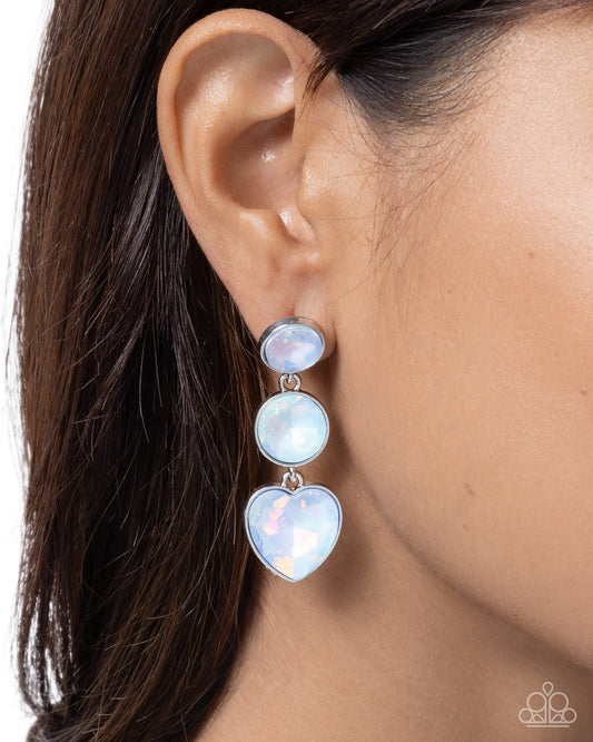Close-up of an ear wearing a silver earring with three heart-shaped opal stones.