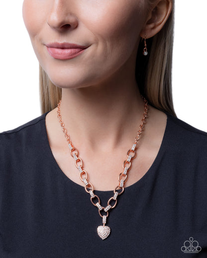 Rose gold chain necklace with heart pendant worn by a model on a white background