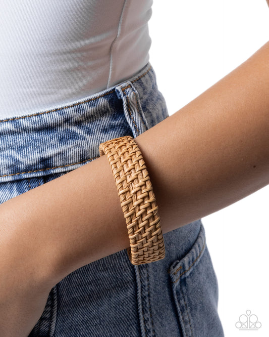 Brown woven bracelet on a wrist with a white background