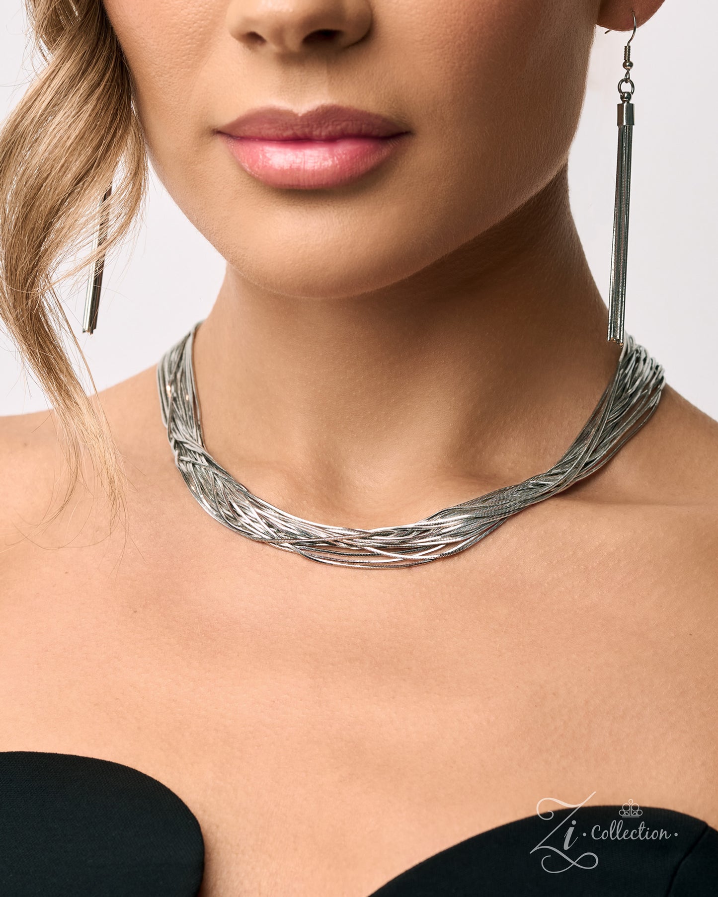 A close-up of a model wearing a textured silver multi-strand twisted choker necklace and matching long drop earrings from The Zi Collection.