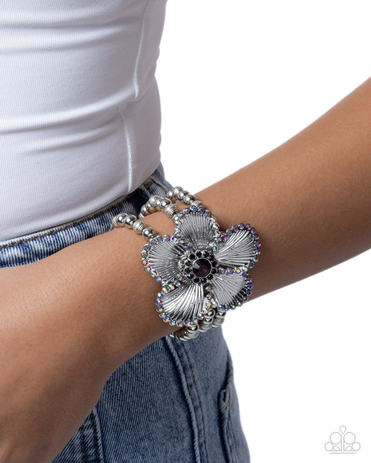 Silver floral bracelet on a wrist with a white background