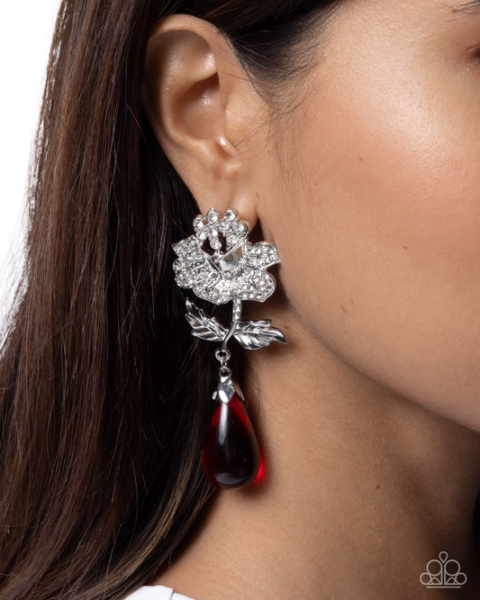 Close-up of a woman wearing a silver and red earring.