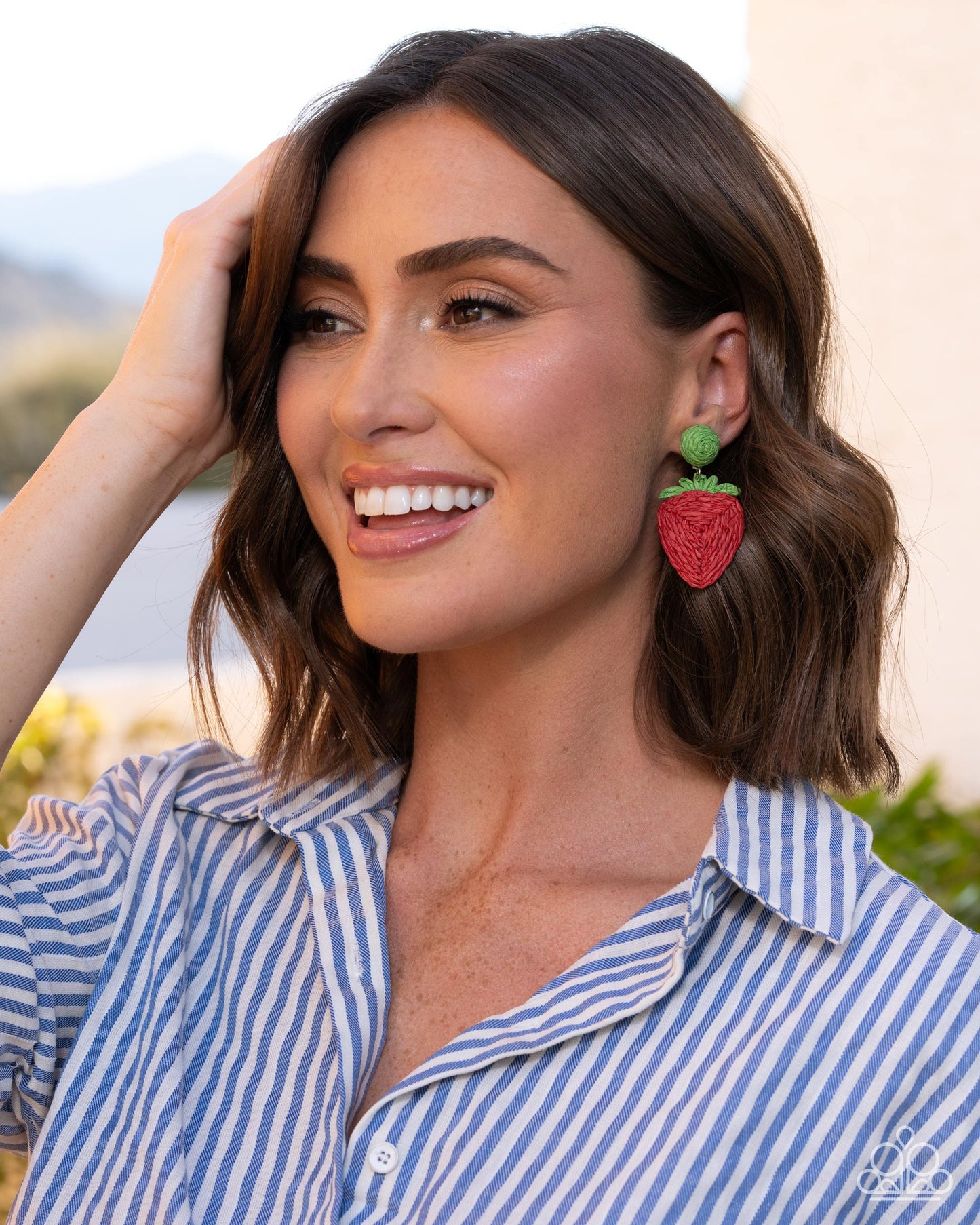 Woman wearing strawberry-shaped earrings outdoors