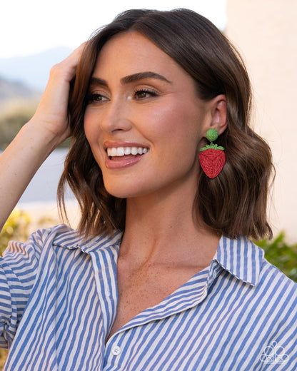 Woman wearing strawberry-shaped earrings outdoors