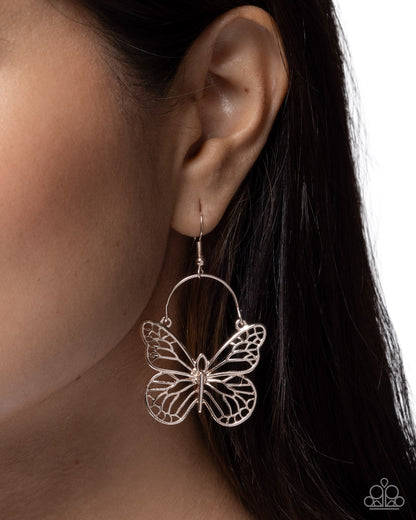 Butterfly-shaped earring worn by a person with dark hair.